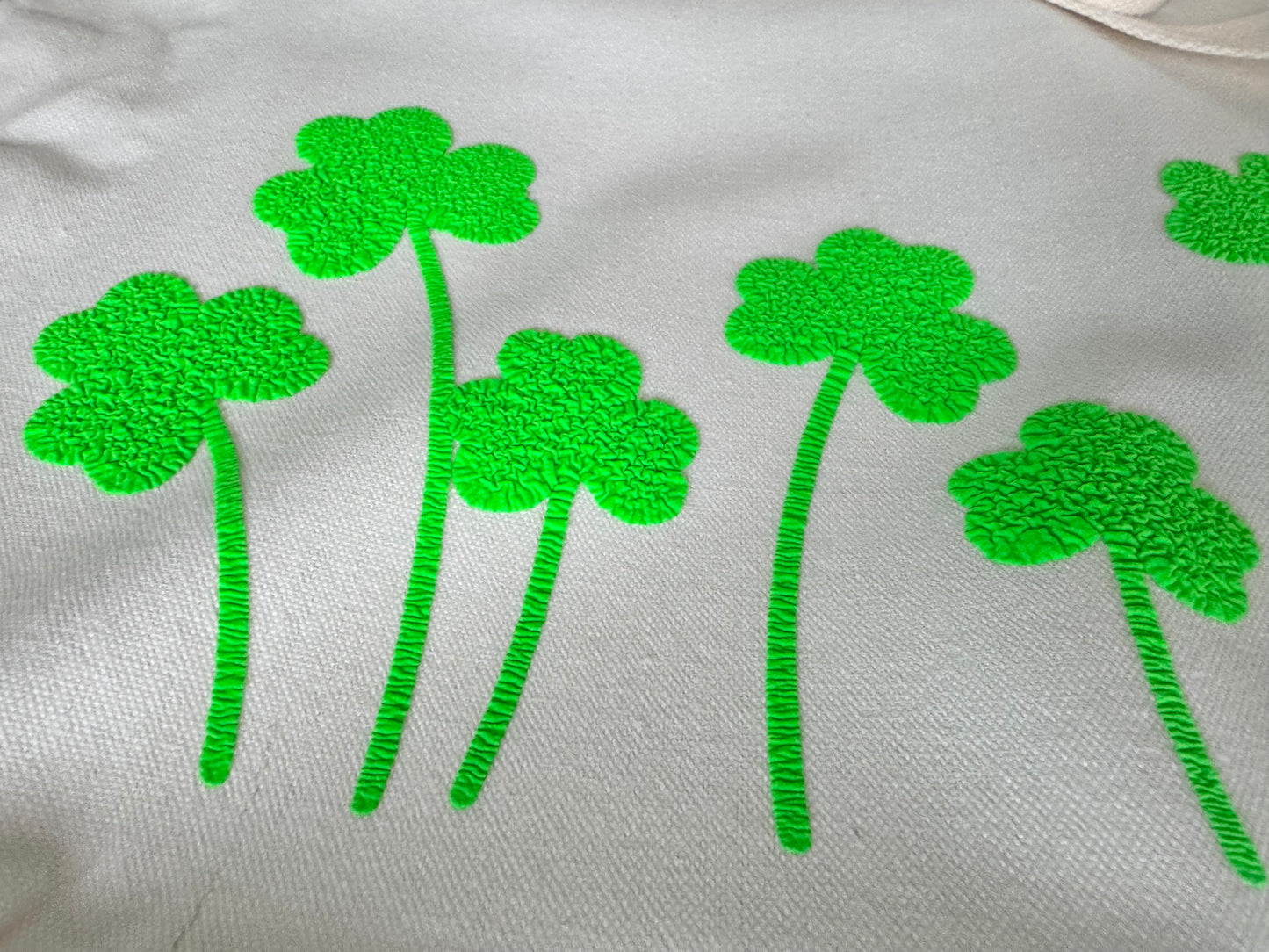 Green puff vinyl shamrock designs on a white fabric background