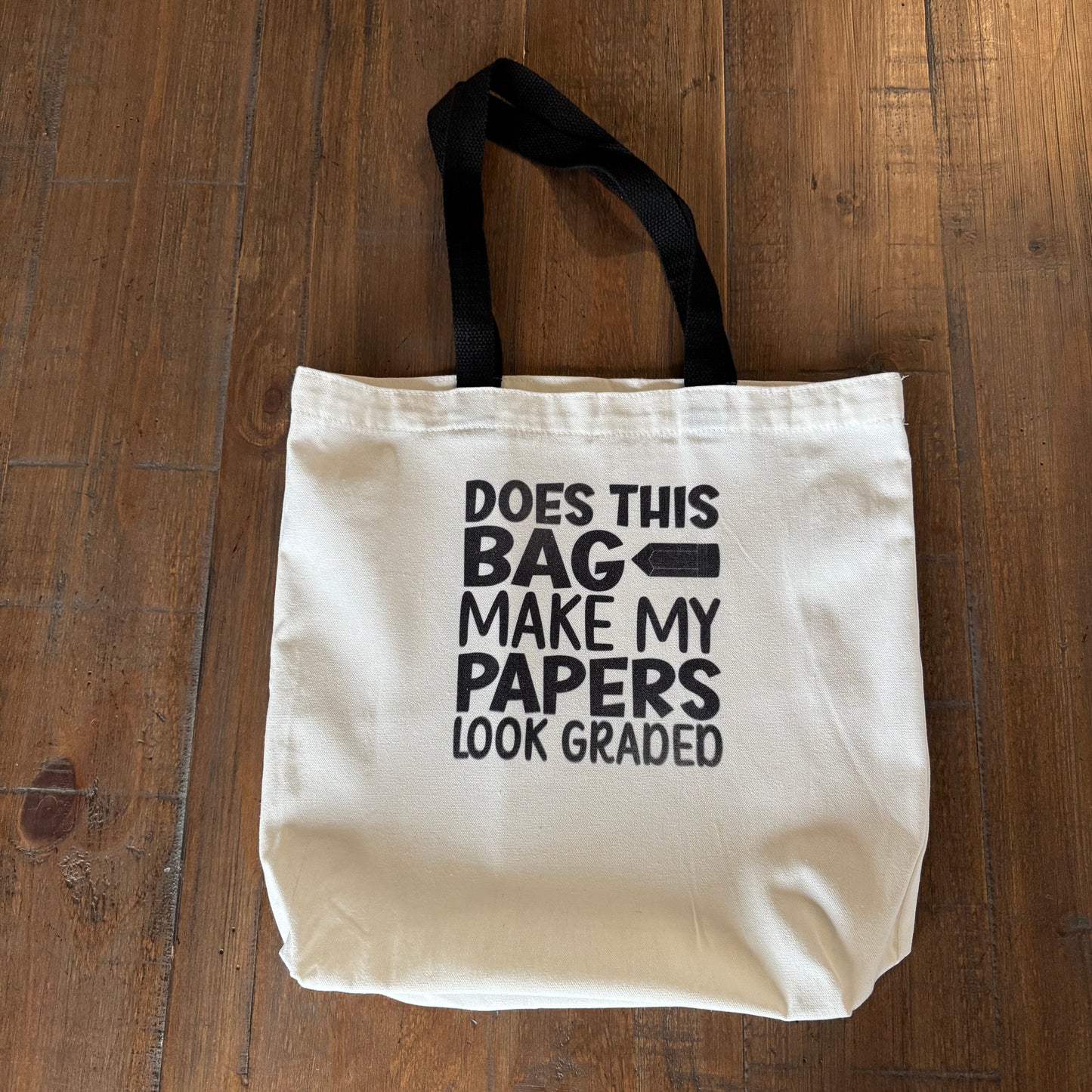 White tote bag with black text on a wooden surface