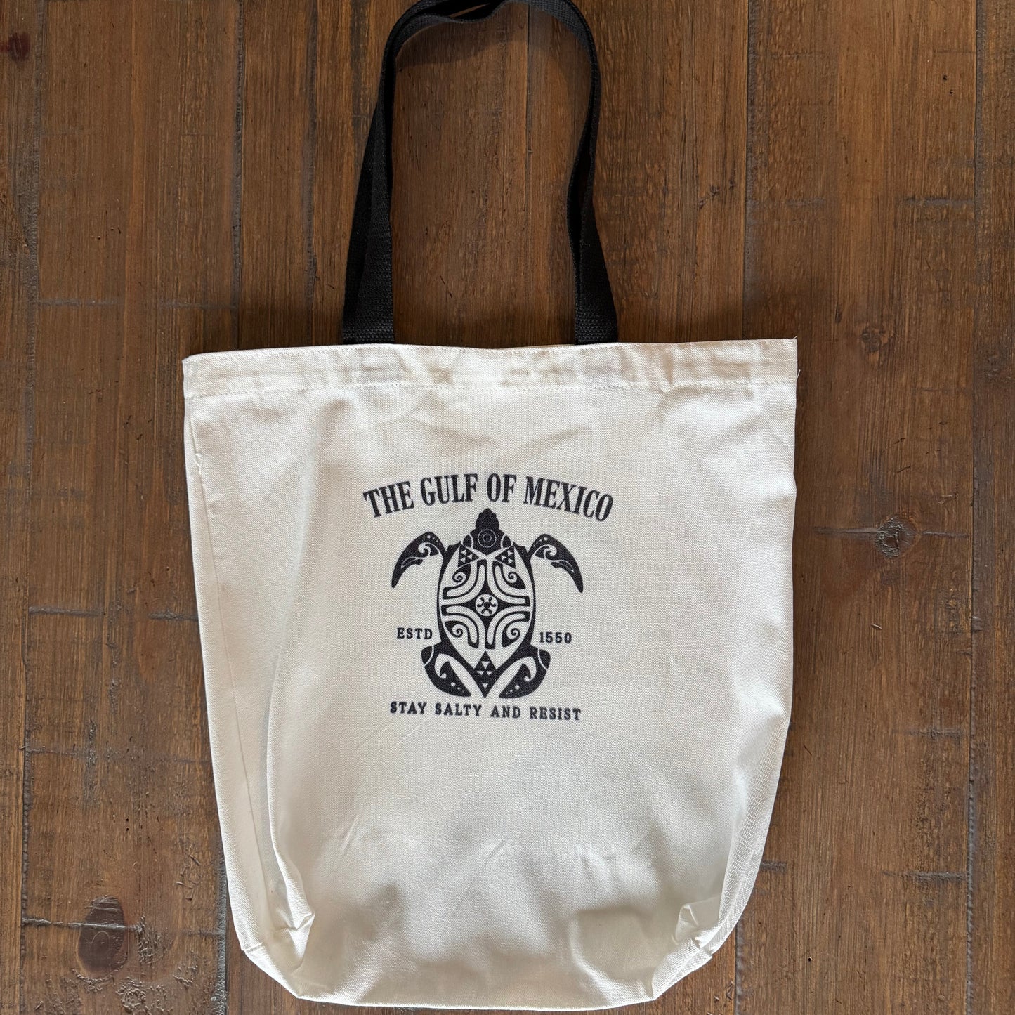 White tote bag with black logo on a wooden surface