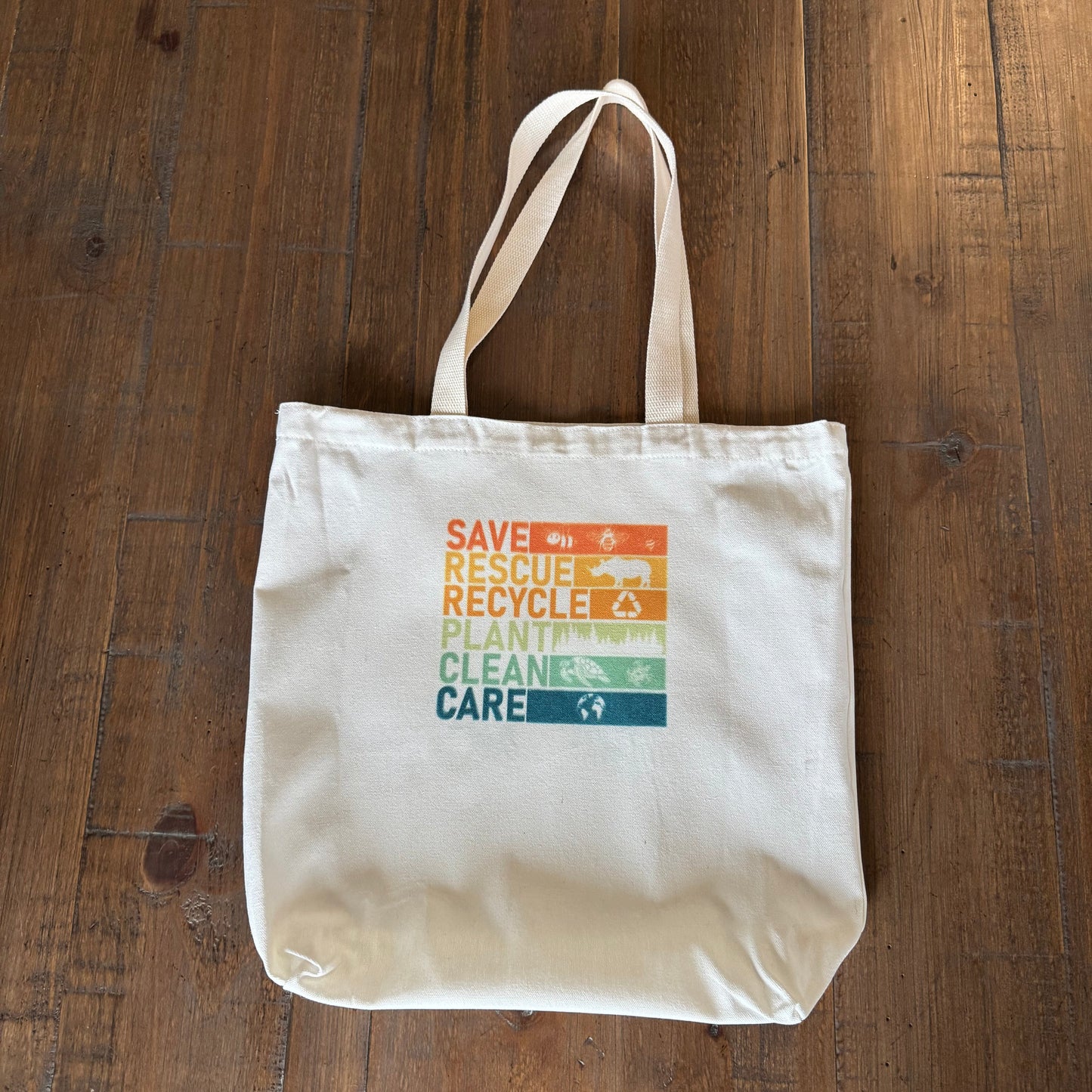 Beige tote bag with colorful text on a wooden surface