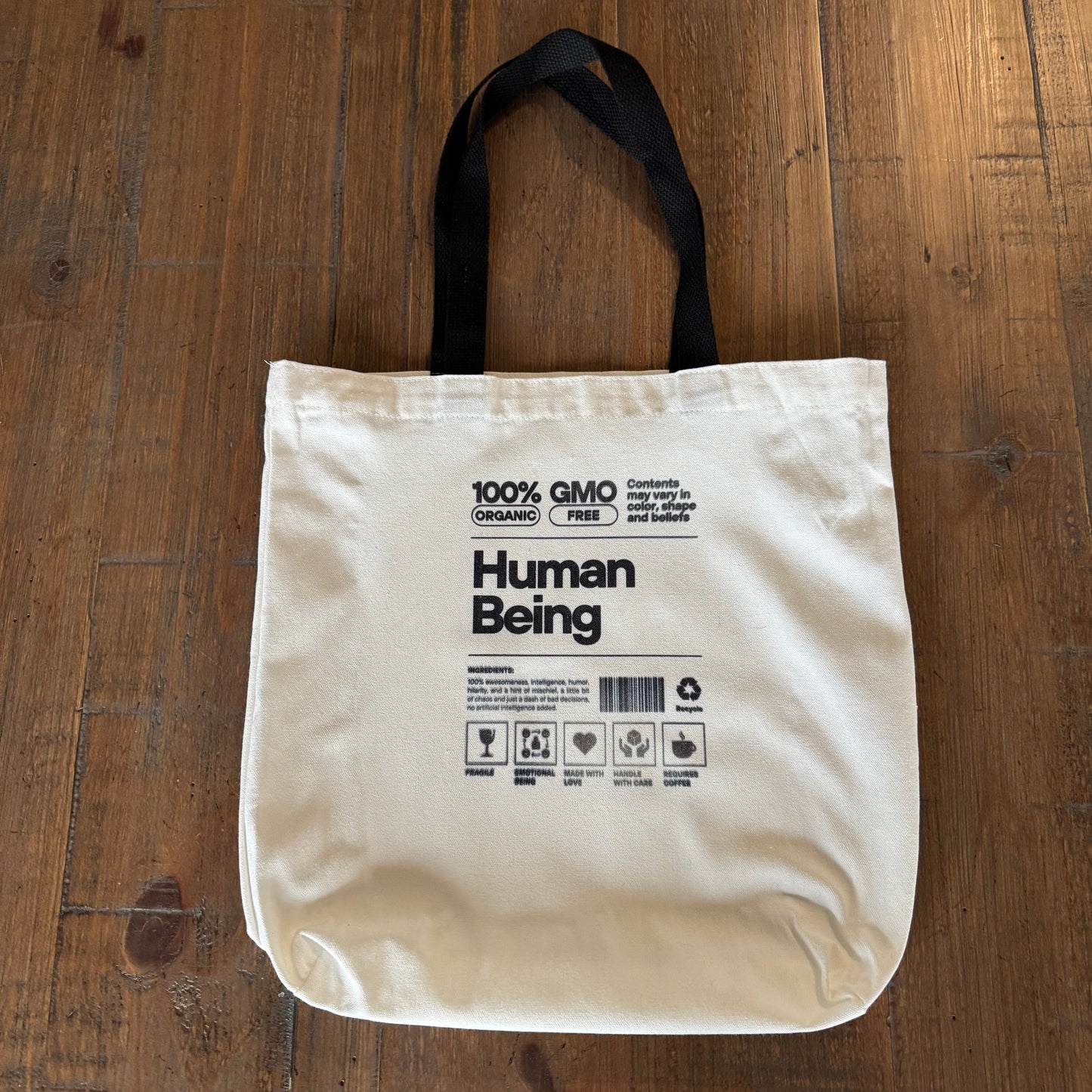 Beige tote bag with text on a wooden surface
