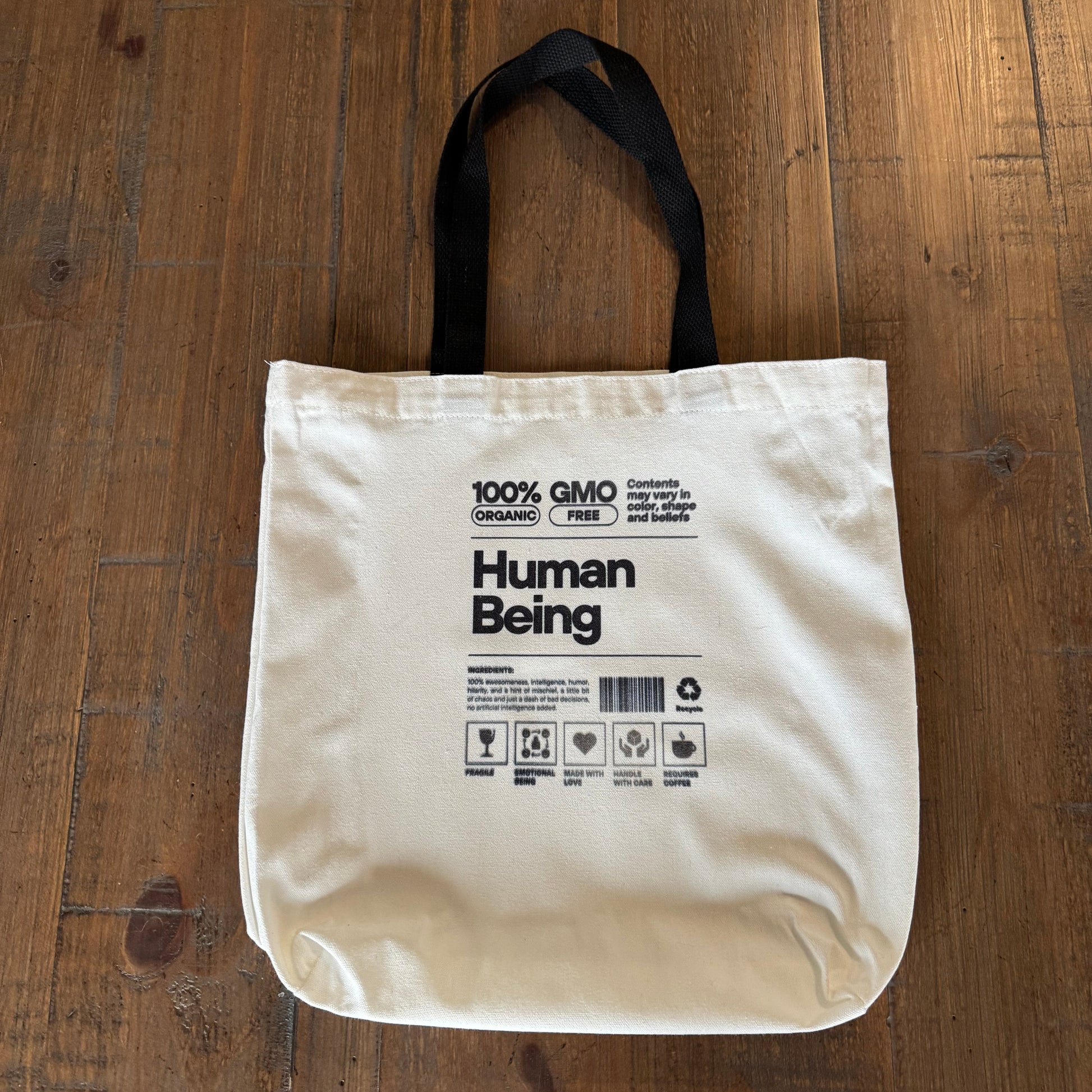 Beige tote bag with text on a wooden surface