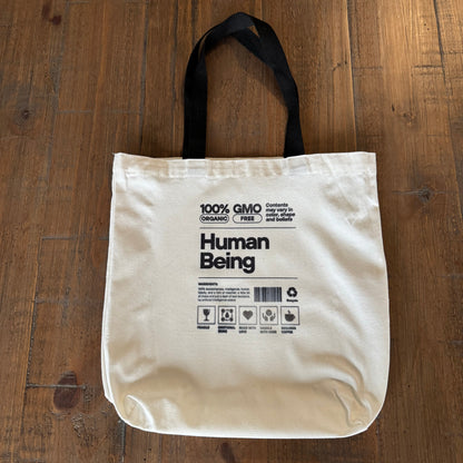 Beige tote bag with text on a wooden surface