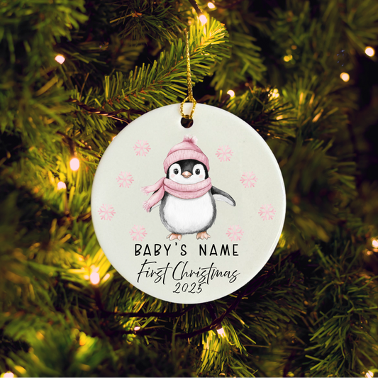 Christmas ornament with a penguin wearing a pink hat and scarf, hanging on a decorated tree.