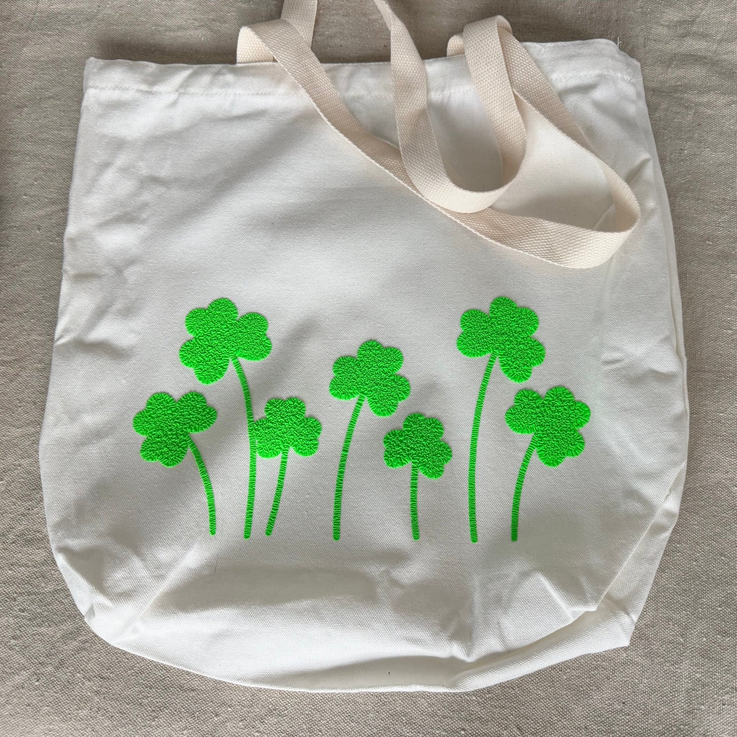 tote bag with green shamrock designs on a beige surface