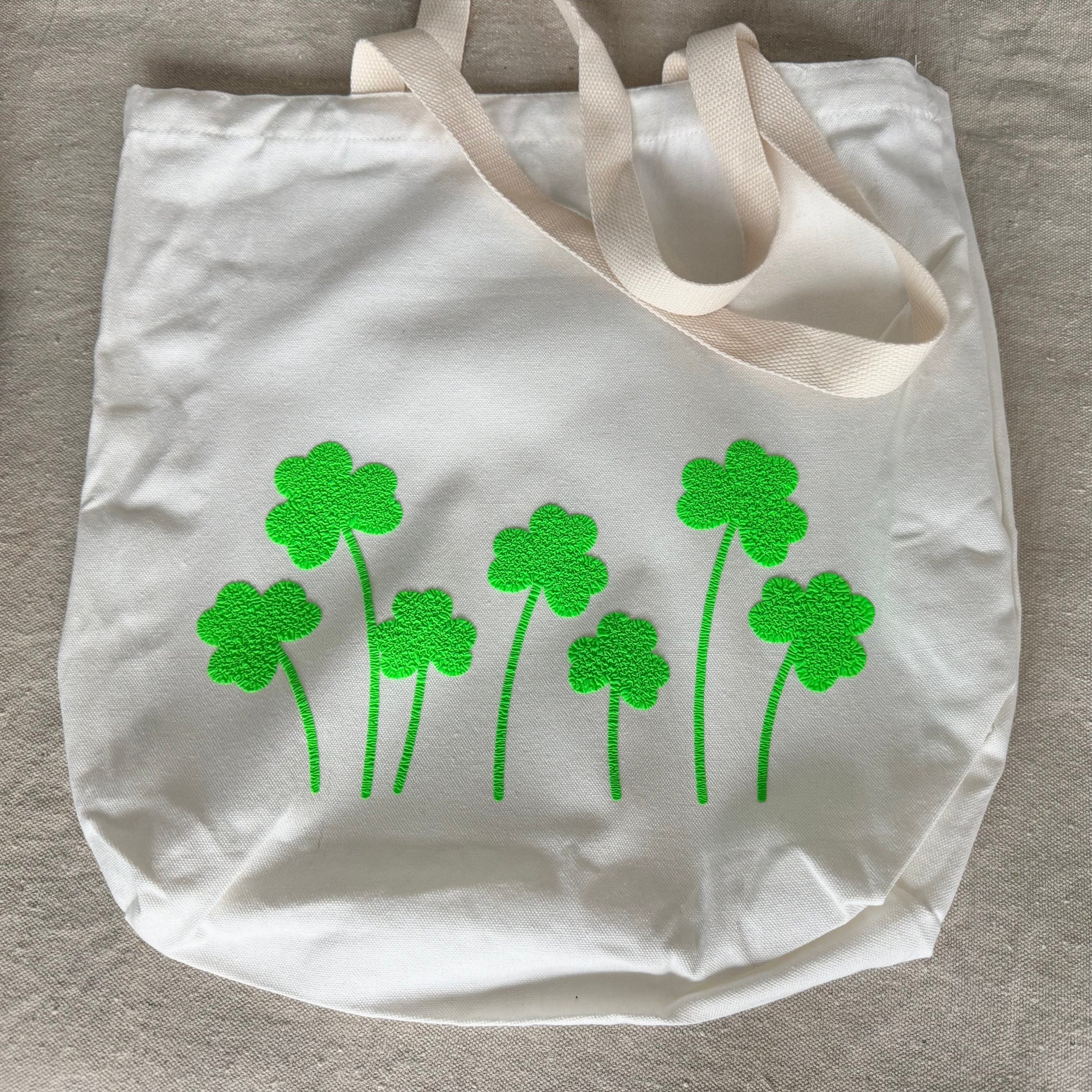tote bag with green shamrock designs on a beige surface