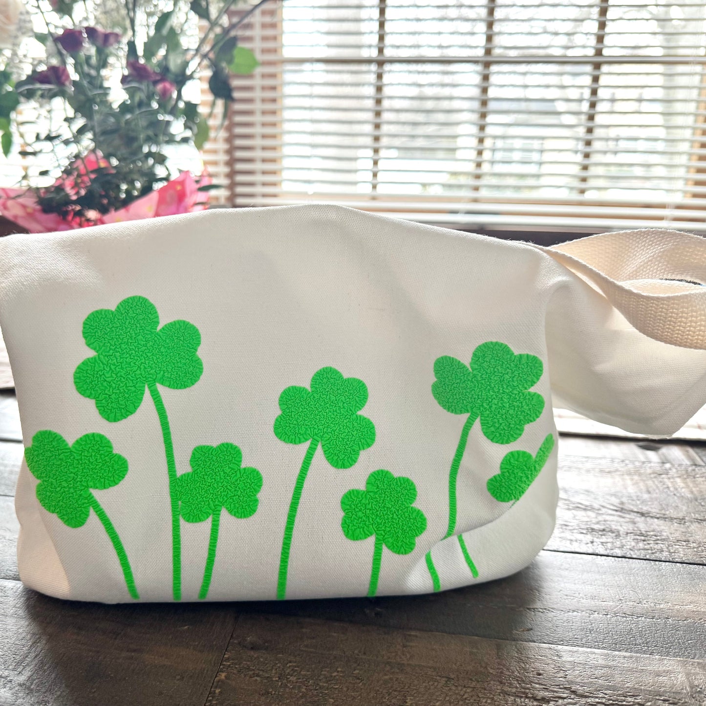 White bag with green shamrock designs on a wooden surface
