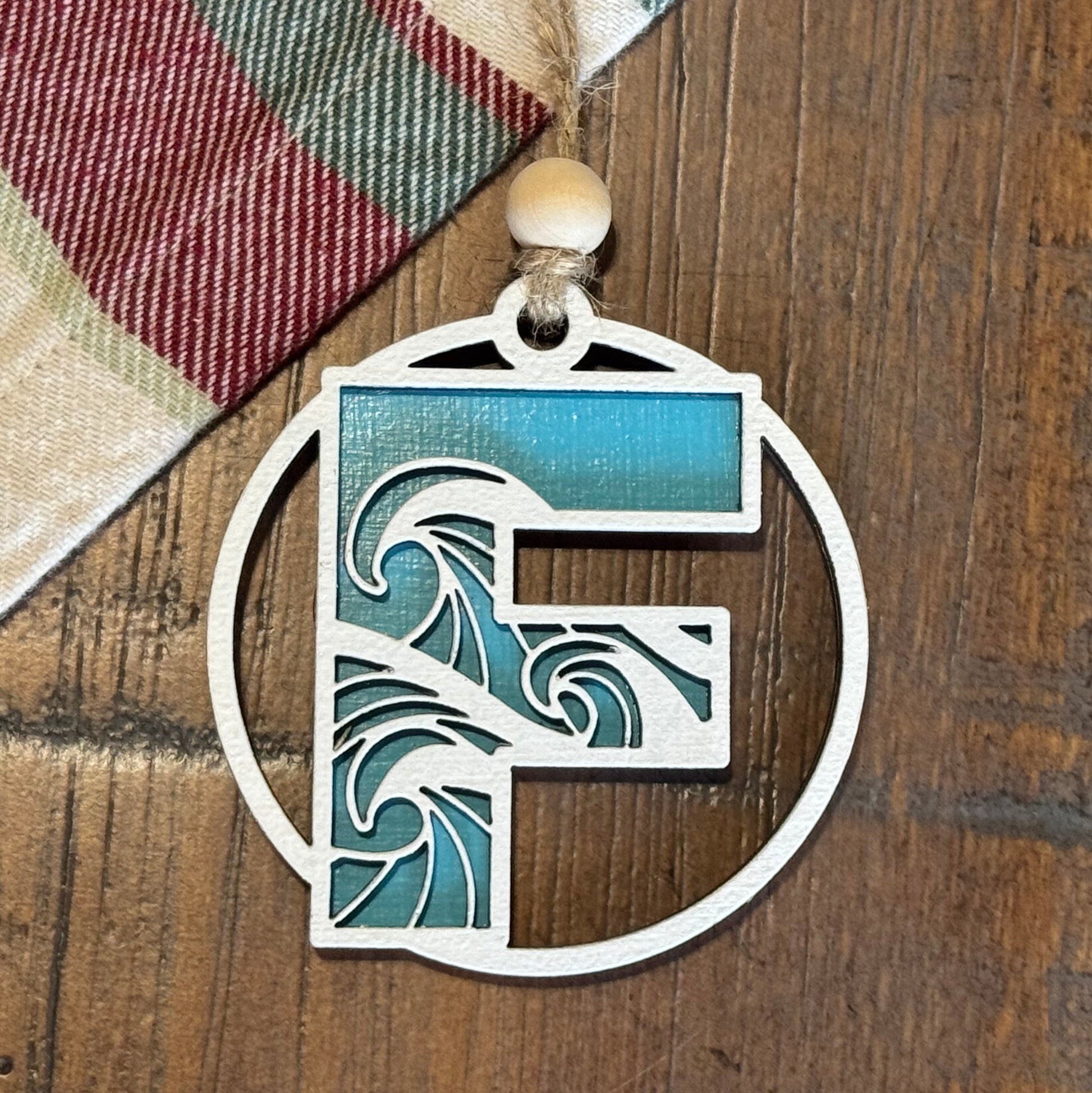 Layered Wave Letter Ornament on a plaid fabric background