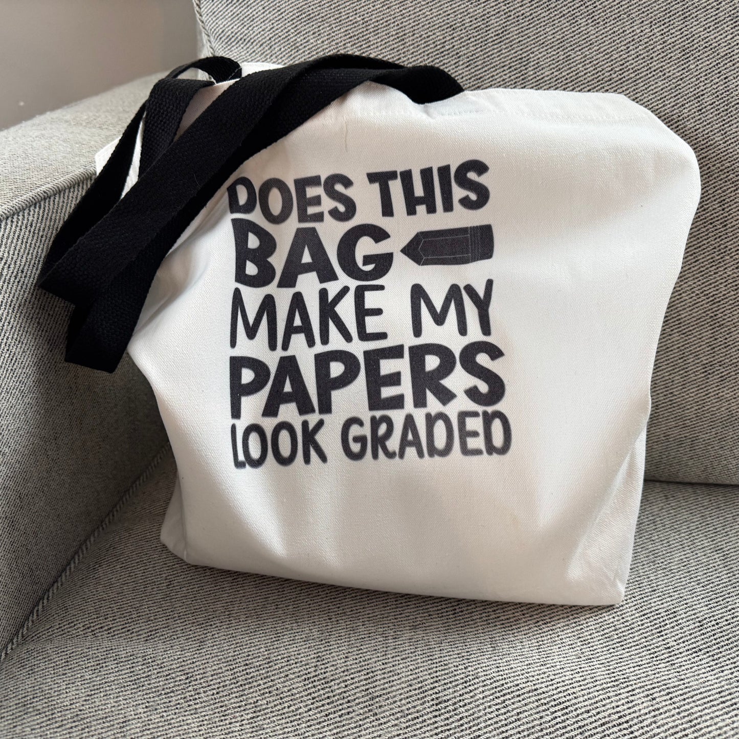 White tote bag with black text on a gray couch