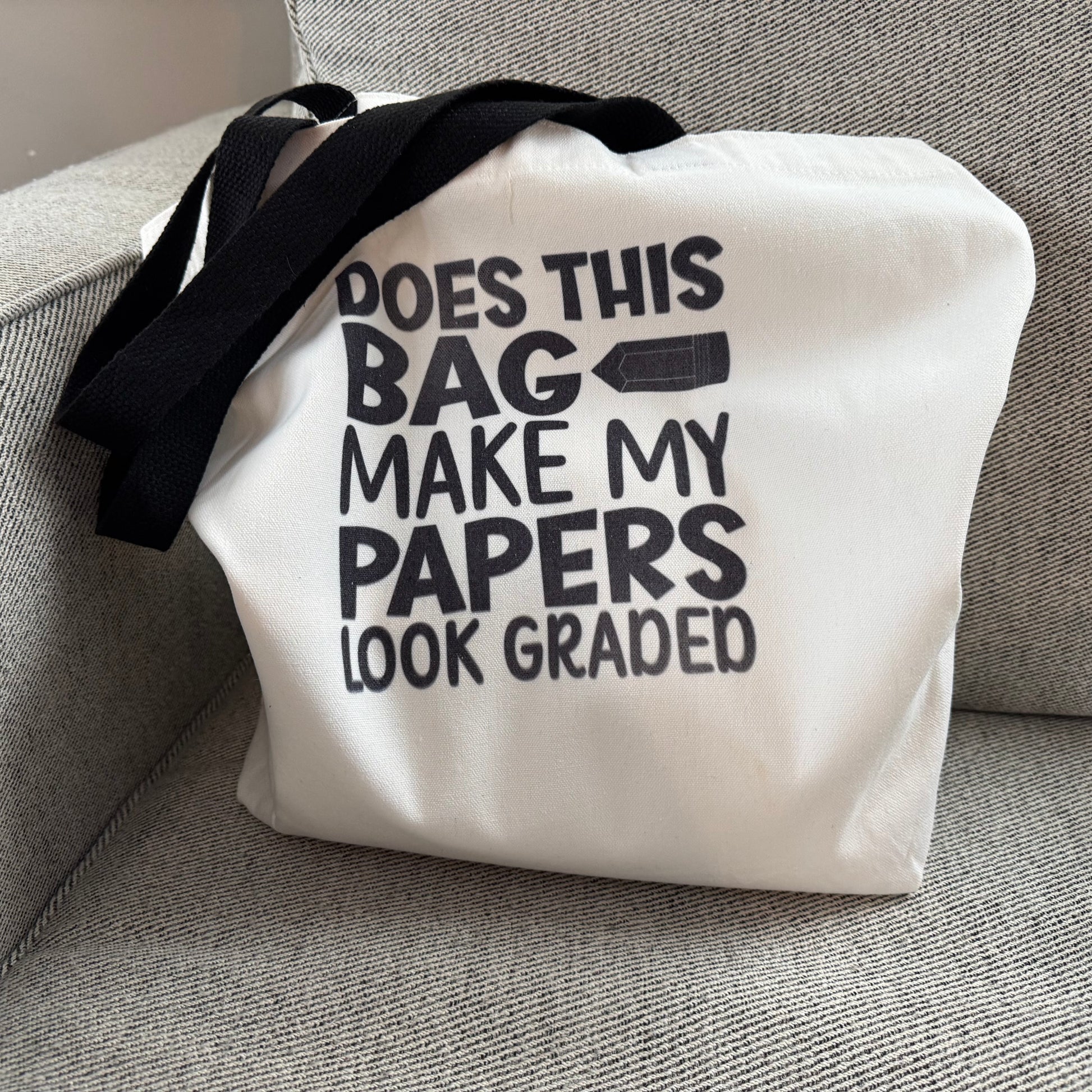 White tote bag with black text on a gray couch