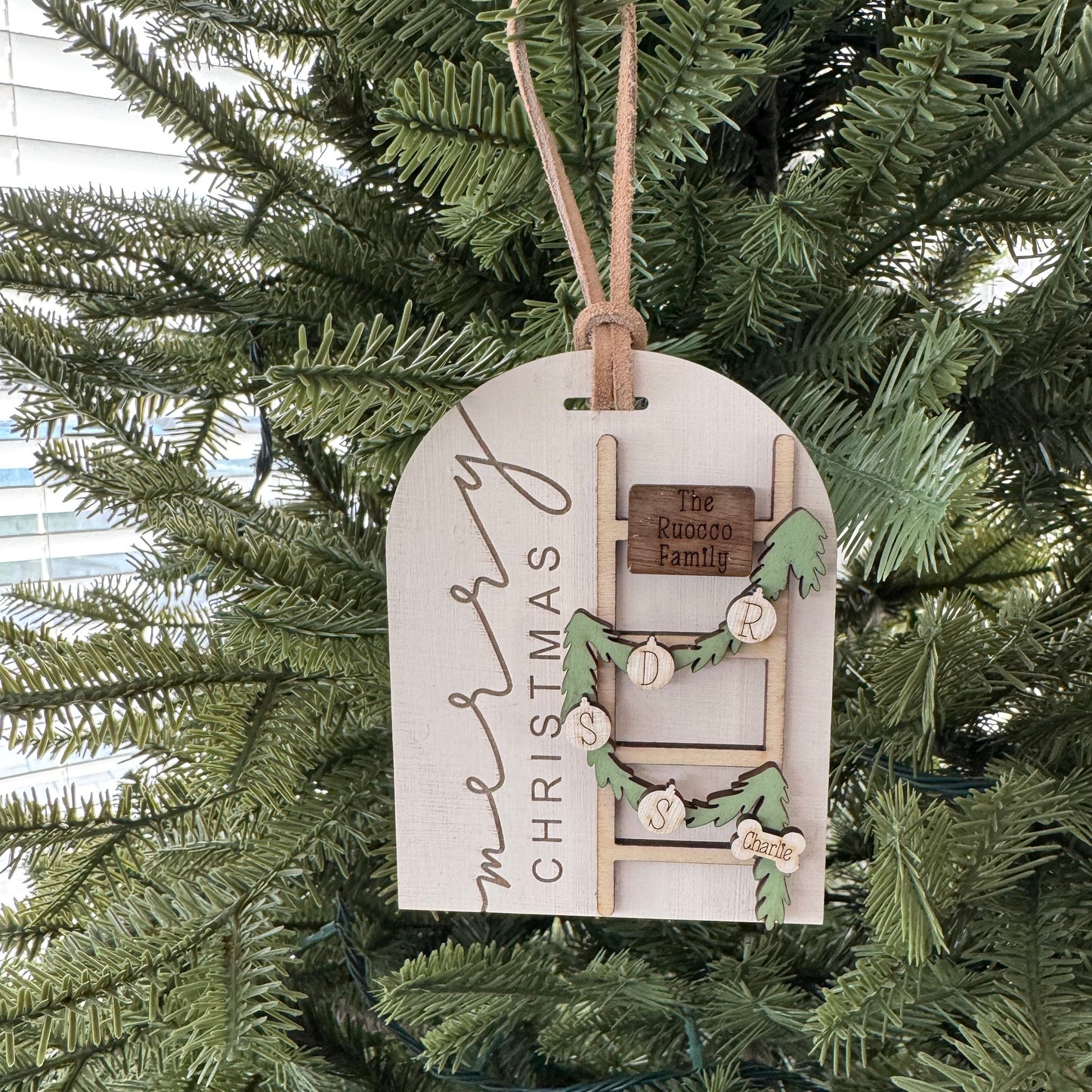 Decorative Christmas tag with a ladder design hanging on a Christmas tree.