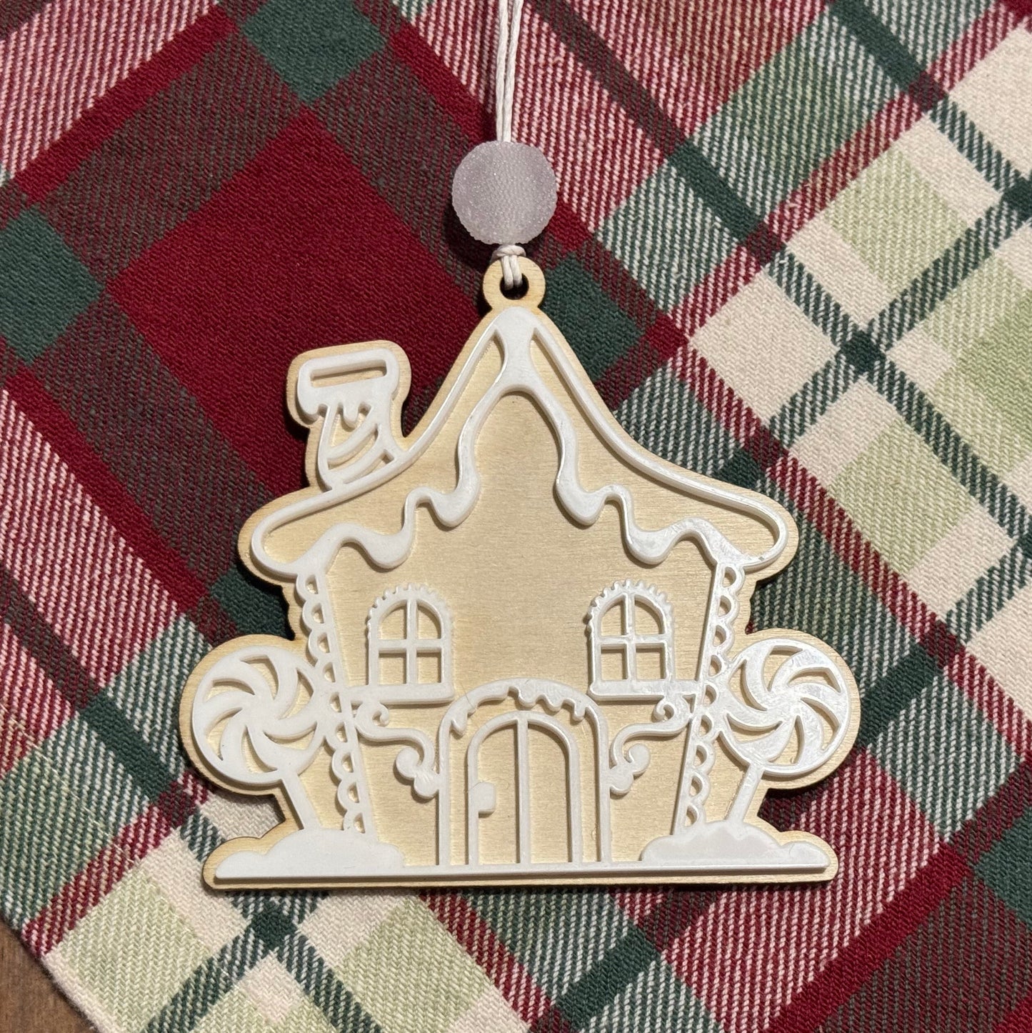 Decorative gingerbread house ornament on a plaid fabric background