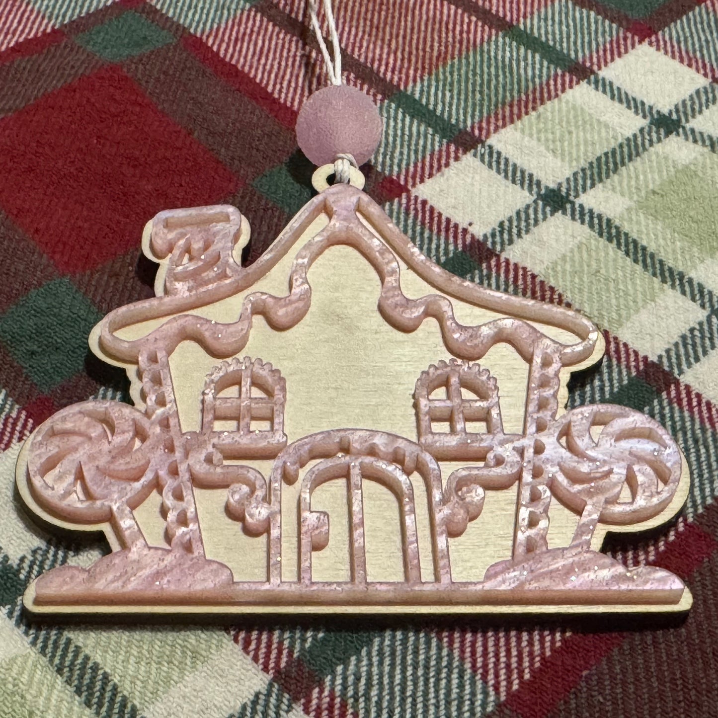 Decorative gingerbread house ornament on a plaid fabric background