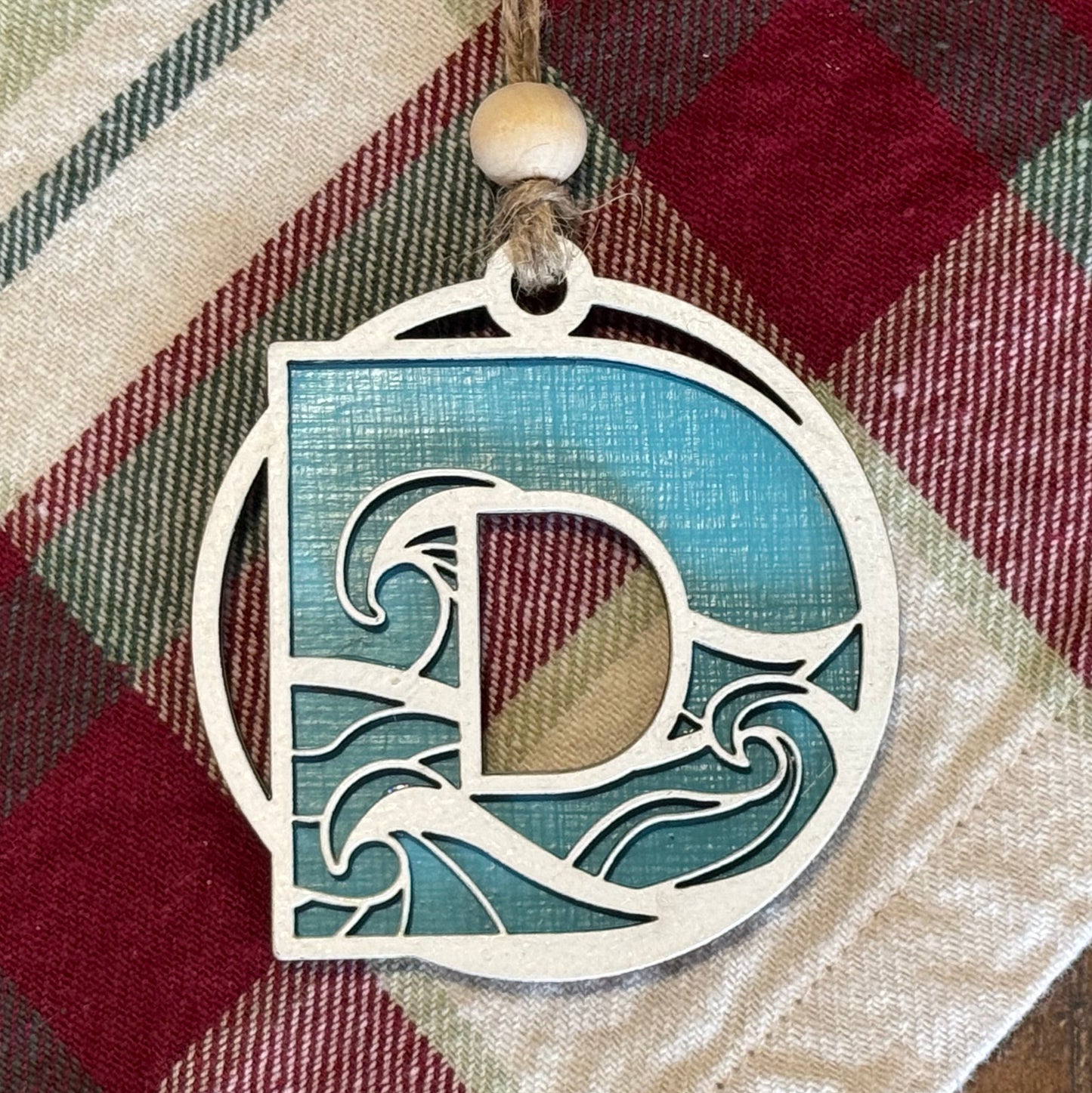 Layered Wave Letter Ornament on a plaid fabric background
