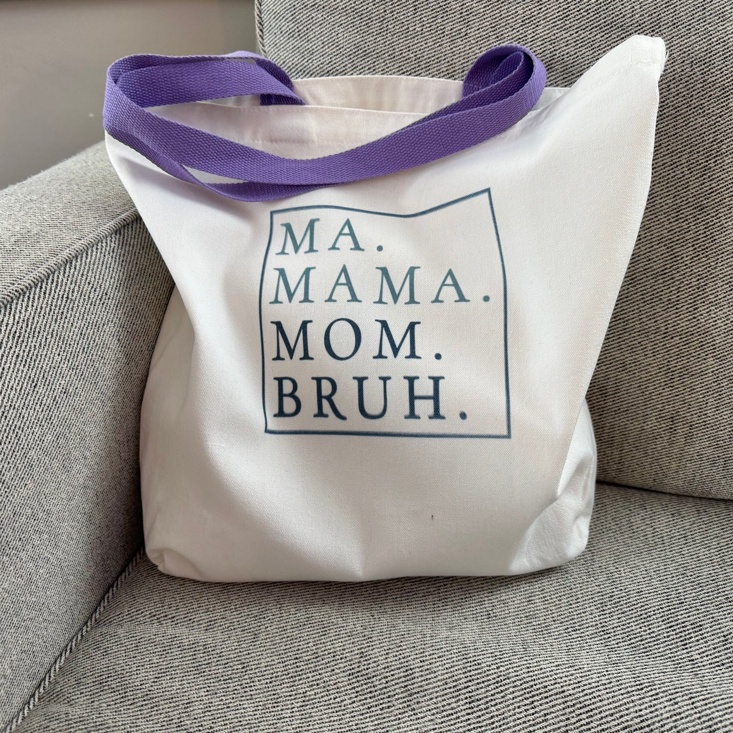tote bag with purple handles and text on a gray chair