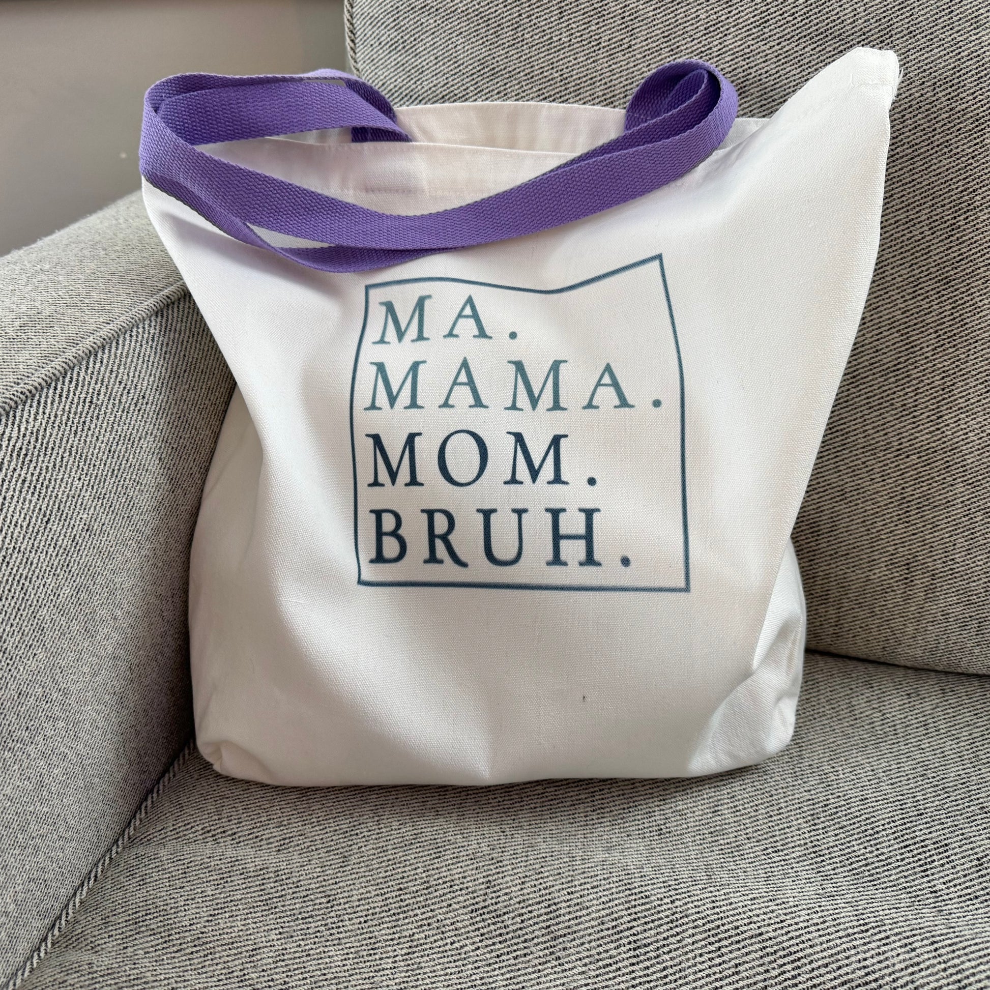 tote bag with purple handles and text on a gray chair