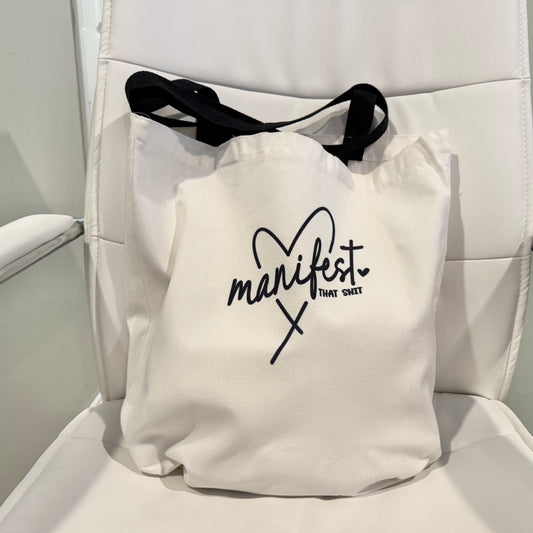  tote bag with 'manifest that shit' text on a white background
