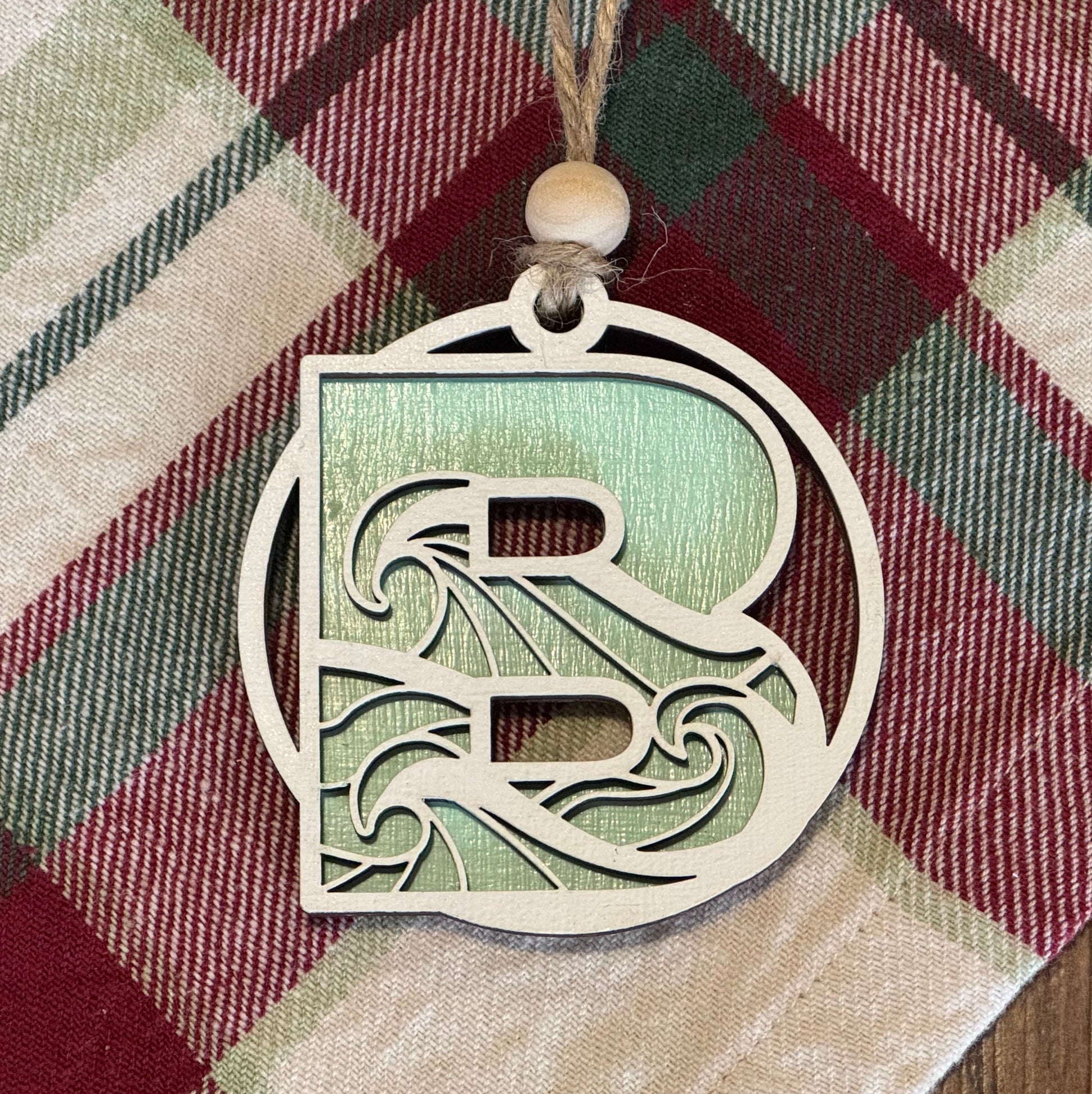 Ocean wave ornament with a letter 'R' on a plaid fabric background