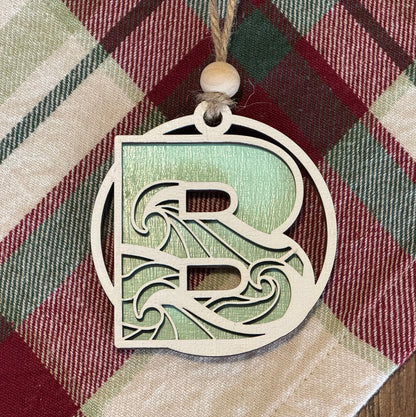Ocean wave ornament with a letter 'R' on a plaid fabric background