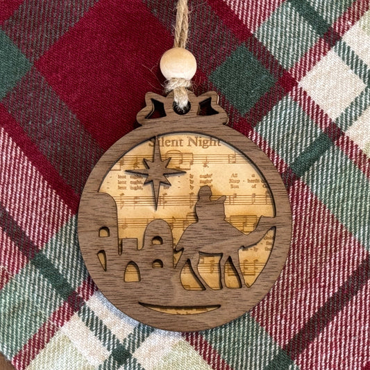 Wooden ornament with nativity scene design on a plaid fabric background