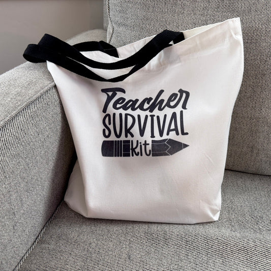 Tote bag with 'Teacher Survival Kit' text on a gray couch