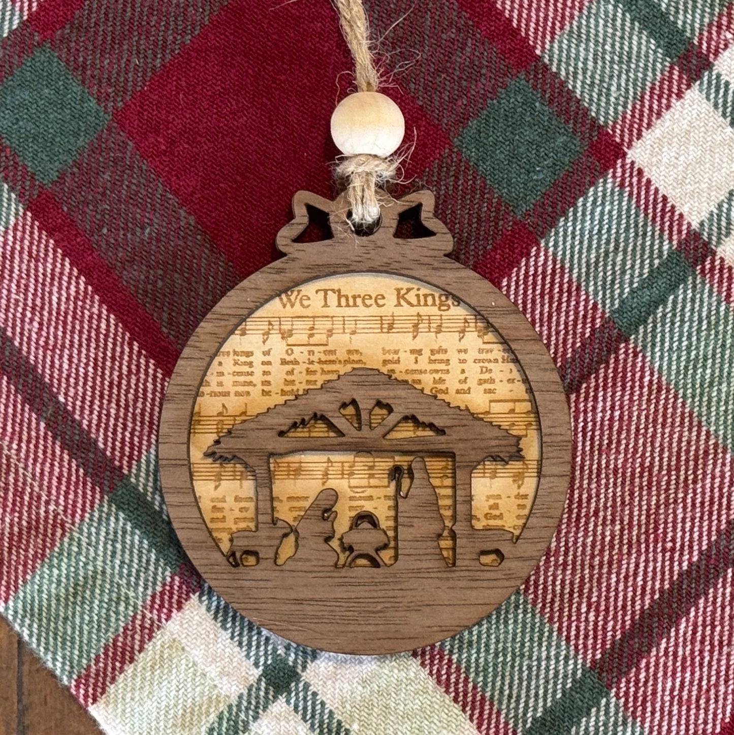 Wooden ornament with nativity scene design on a plaid fabric background